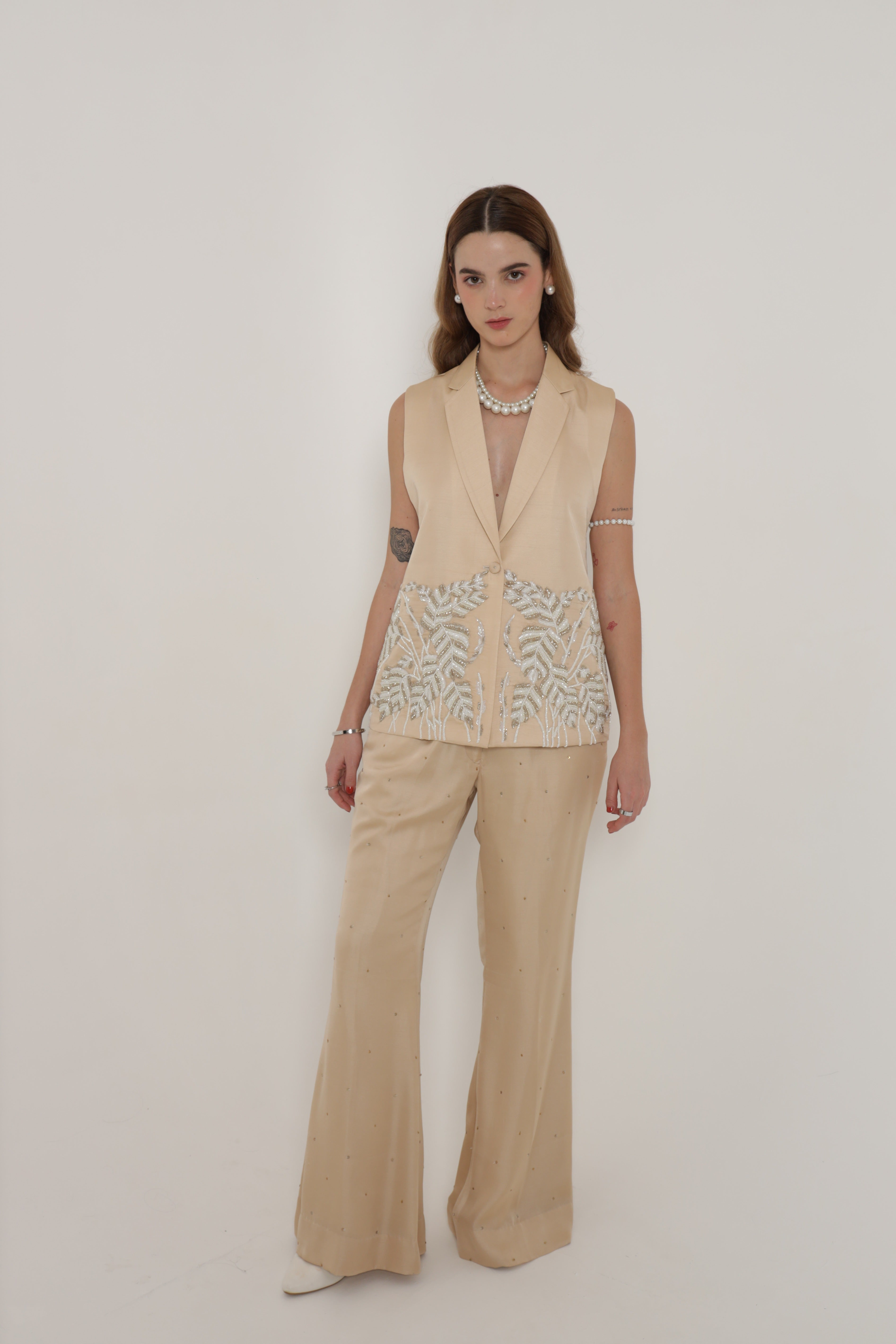 Beige sleeveless jacket with bell bottom pants and bustier