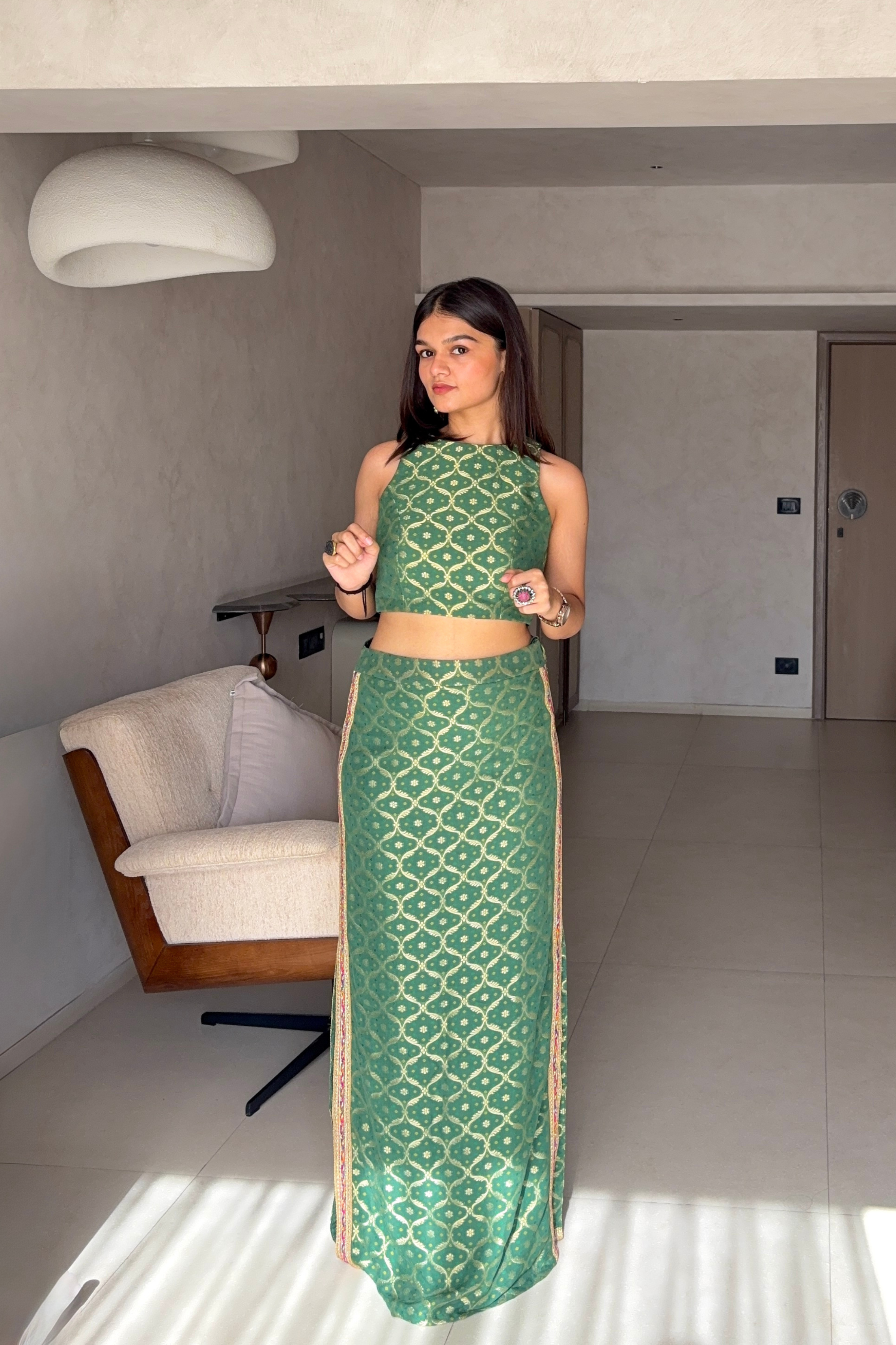 Woman in a green patterned outfit standing in a modern room.