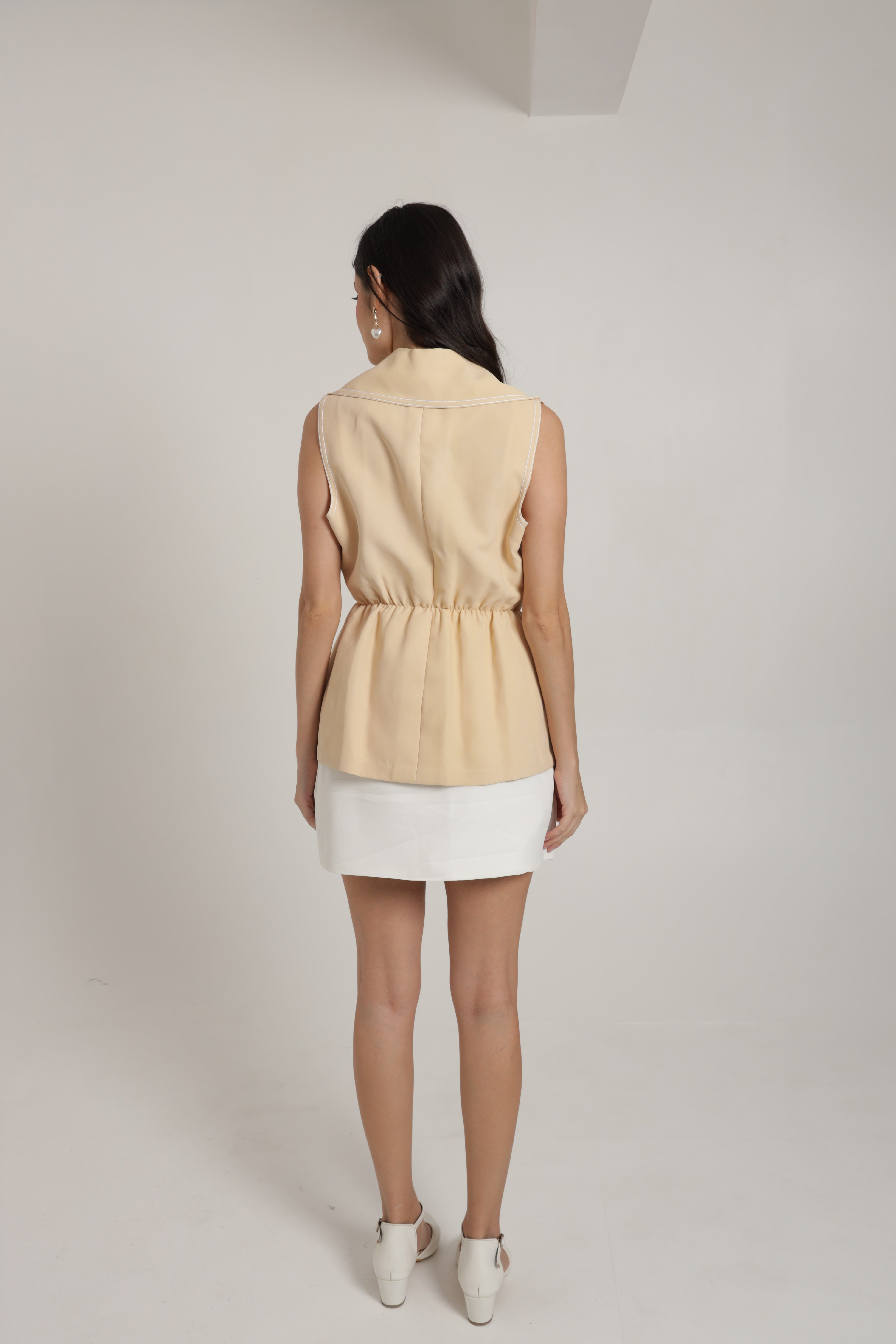 Beige sleeveless jacket with white skirt