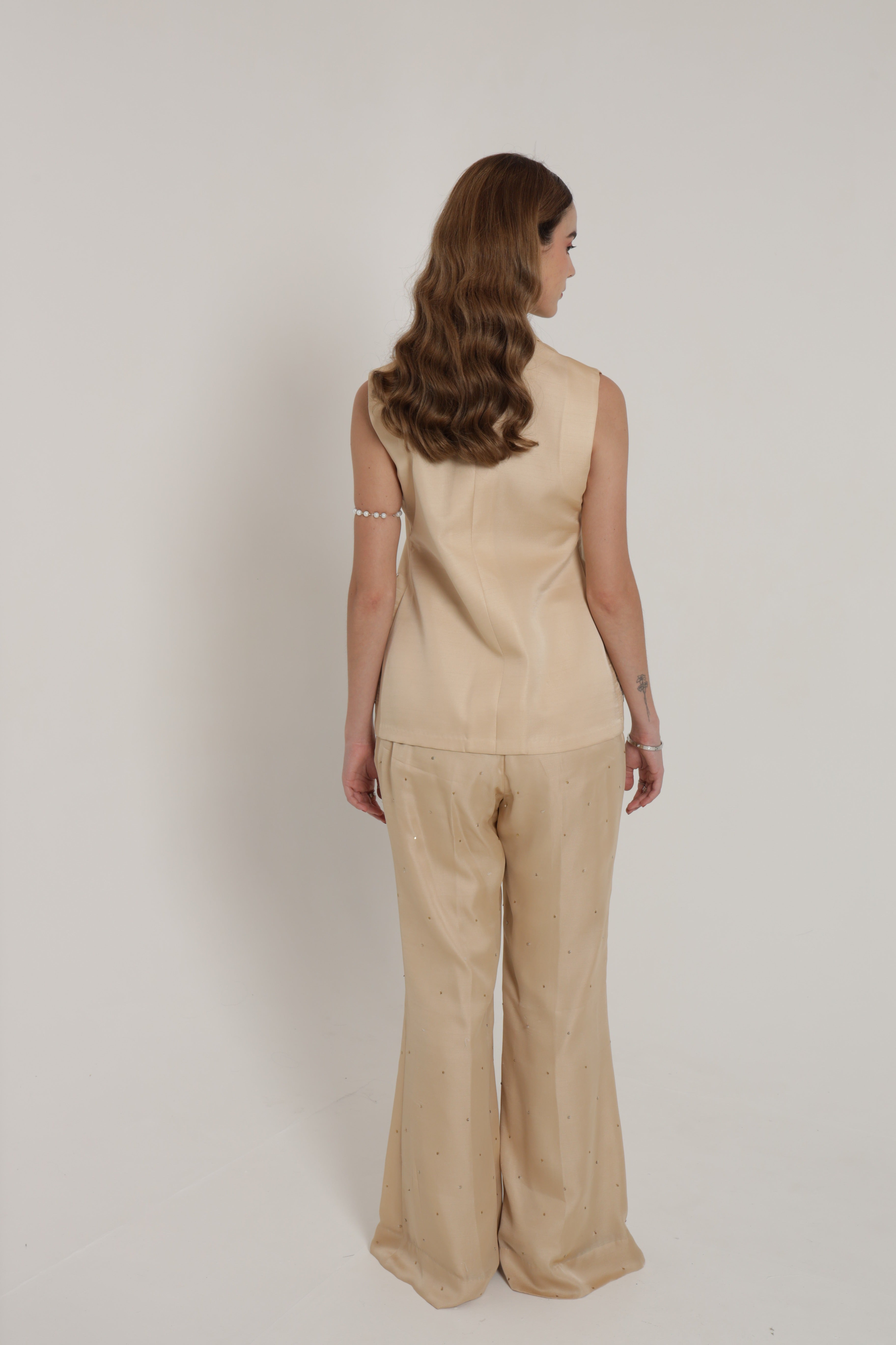 Beige sleeveless jacket with bell bottom pants and bustier